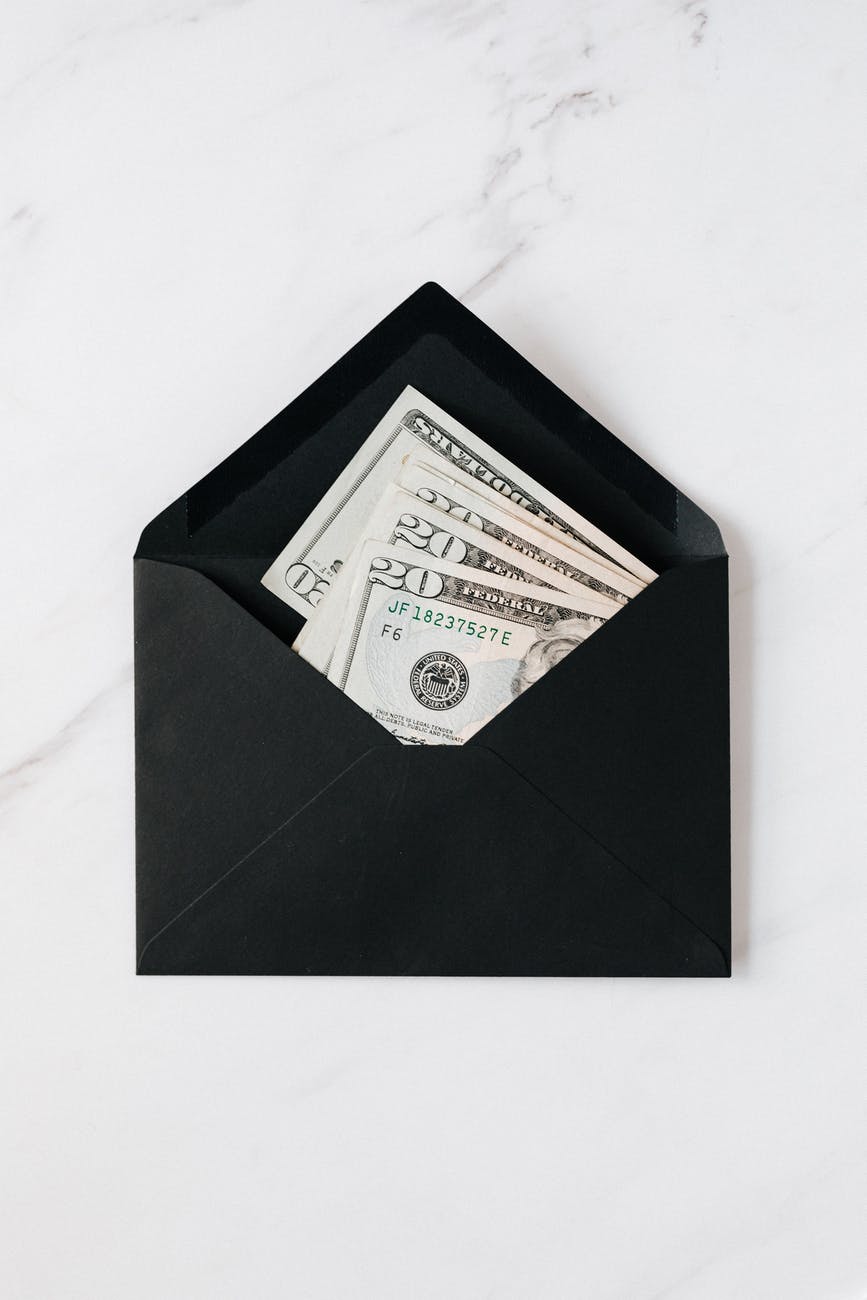 black envelope with cash dollars on marble table
